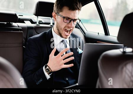 Young businessman using laptop sitting in car Stock Photo