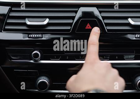 Man pressing red triangle car hazard warning button Stock Photo