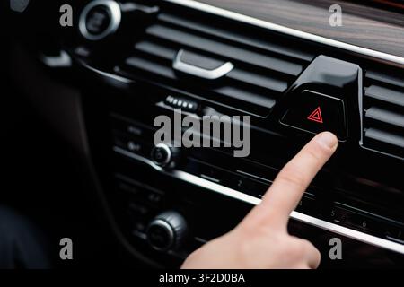 Man pressing red triangle car hazard light button Stock Photo
