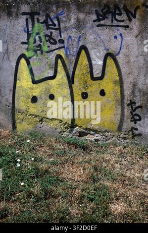 Szentendre, Hungary - July 04, 2026: Bright yellow cat graffiti art painted on weathered concrete wall with urban tags. Stock Photo