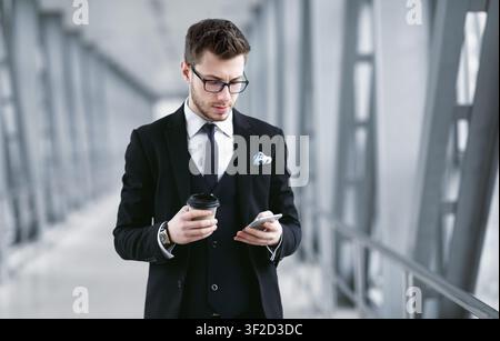 Focused business man texting on cell phone, drinking coffee Stock Photo