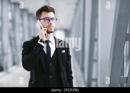 Serious business man talking on smartphone wearing specs Stock Photo
