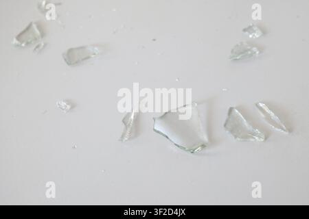 Broken Glass Shards on White Tile Surface Stock Photo
