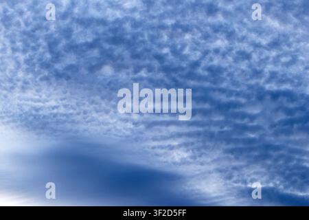 Altocumulus clouds are mid altitude clouds consisting of patches or layers of regularly spaced clouds, or cloudlets. These seldom result in rain Stock Photo