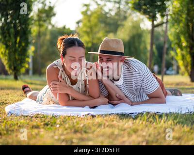 Cheerful multiracial couple is smiling and having fun in park in summertime. Stock Photo