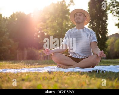 Adult man is practicing yoga in park in summertime. Lotus position. Stock Photo