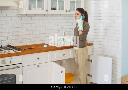 Housewife complains on clogged sink calling plumber service for fixing, fit, repair pipes, fittings Stock Photo