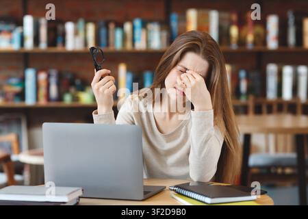 Tired woman working on laptop and holding hand on bridge Stock Photo