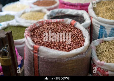 Assorted raw grains, pulses, and peanuts displayed in open burlap sacks at a traditional wet market Stock Photo