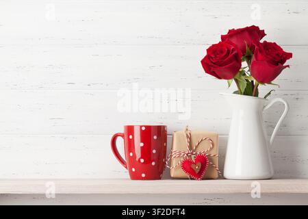 Valentines day greeting card with rose flowers and gift box on white wooden background. With space for your greetings Stock Photo