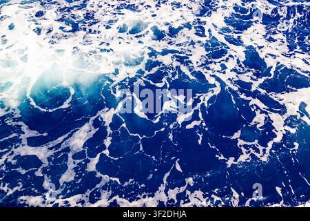 Top down view of deep blue sea water surface with dynamic white foam trail ripples and liquid abstract texture Stock Photo