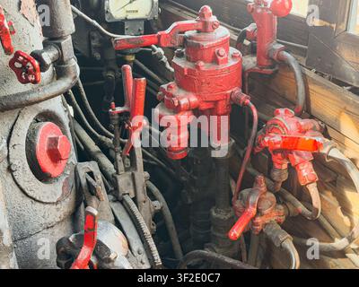 Vintage steam locomotive cab interior details, intricate metal components, valves, levers, pipes, red paint chipping, rusted metal parts, aged appeara Stock Photo