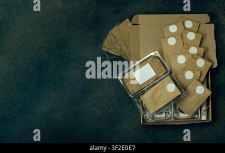 Flat lay composition presents indoor gardening kit with eco friendly materials. Brown kraft paper bags with circular white stickers contain seeds read Stock Photo