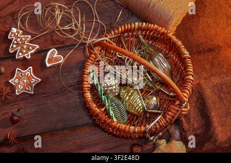 Decorated gingerbread cookies in snowflake, heart, and mitten shapes are scattered across aged wood planks alongside star anise and acorns. Handmade g Stock Photo