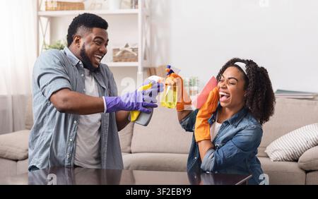 Happy Housekeeping. Cheerful black couple having fun while doing housework together Stock Photo