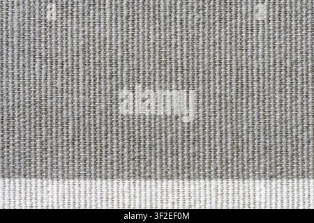 A close-up view shows a textured fabric with a prominent weave pattern. The top two-thirds of the image is a light gray woven material, transitioning Stock Photo