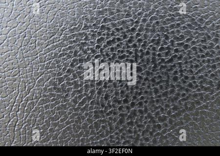 A close-up shot showcases the detailed texture of dark gray faux leather. The surface exhibits a pattern of raised, irregular ridges and dimples. Stock Photo