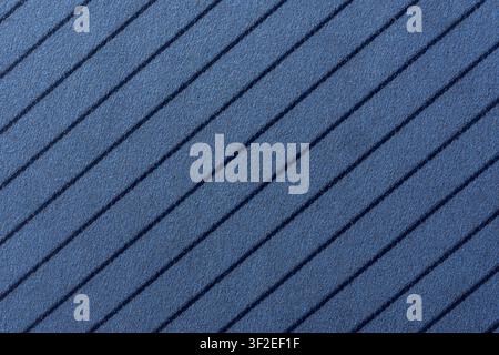 A close-up, high-angle view of a blue, textured surface featuring parallel, dark blue diagonal stripes. The texture appears to be that of fabric or pa Stock Photo