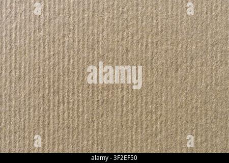 The image shows a close-up view of a textured, light brown cardboard surface. The texture consists of vertical parallel lines or ridges. Stock Photo