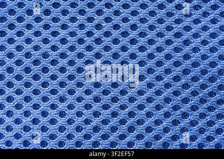 A close-up shot shows a blue, perforated mesh fabric. The hexagonal pattern of the weave is clearly visible throughout the image. Stock Photo