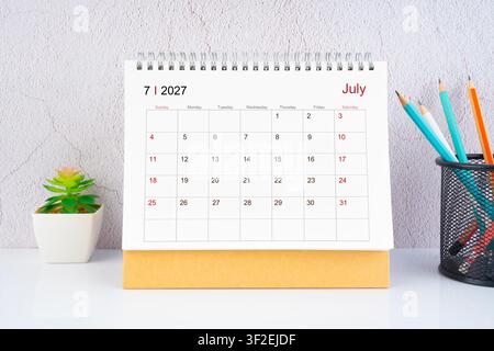 July 2027 Desk Calendar with wooden pencil on table. Stock Photo