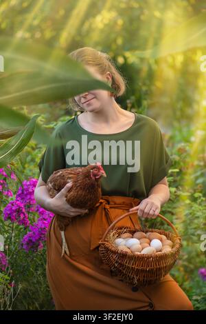 Fresh eggs rest in woven basket while female farmer holds red hen after collection from nest. Organic poultry farming with fresh eggs and red hen. Stock Photo