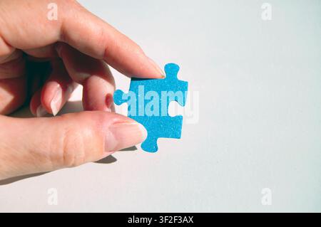 hand holding a blue puzzle piece Stock Photo