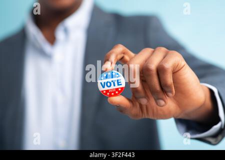 African man holding vote button on blue background Stock Photo