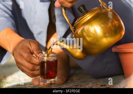 Traditional Arabic tea being poured into a glass from a brass teapot in Saudi Arabia Stock Photo
