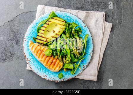 Green salad with grilled avicado and grilled chicken in blue plate Stock Photo