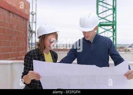 Architects and engineers collaborating on a building site, reviewing blueprints, planning construction, ensuring safety and professional project devel Stock Photo