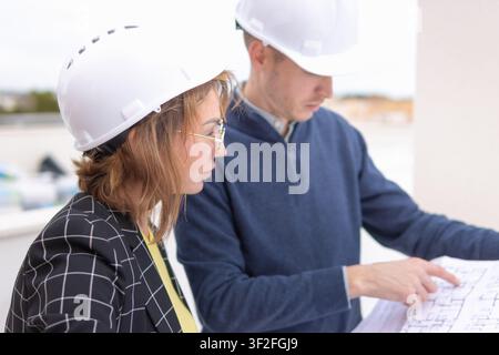 Engineering professionals collaborating on construction blueprints and architectural plans, discussing design details and project specifications while Stock Photo