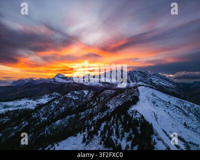 Aerial view of snow-covered peaks in La Giettaz during a vibrant sunset with glowing orange and purple clouds over the alpine landscape in La Giettaz, Stock Photo