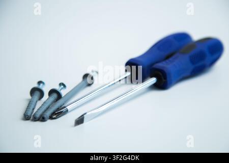 Close-up of two hands in work gloves holding screwdrivers against a white background. Concept of Stock Photo