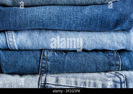 Stack of folded blue denim jeans in various washes and textures, textile background, the different shades of indigo and light blue create a rich texti Stock Photo