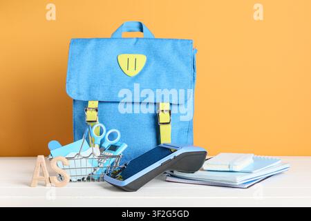 Blue school backpack with payment terminal and stationery for back to school shopping concept, Wooden letters "AS" are placed next to the basket Stock Photo