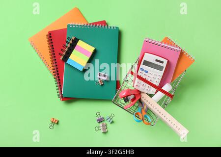 Colorful school and office supplies with notebooks calculator and stationery on a green background education and back to school Stock Photo