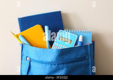 Blue backpack with school supplies including books, calculator, pens, and pencil, ready for education Stock Photo