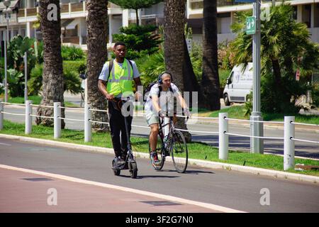 Riding a scooter and a bicycle on the bike path on the promenade in Nice Stock Photo