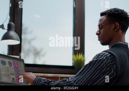 Businessman uses a laptop to review financial paperwork, sales data and investment planning for commercial growth in a focused company office. Stock Photo