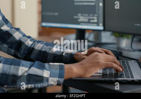 Programmer Typing Machine Learning Code on Laptop in a software development office, showing programmers collaborating on source code, algorithms and data coding workflow. Stock Photo