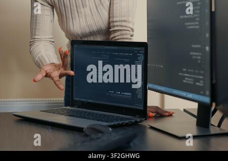 Laptop Compiling Algorithm Beside Developer Team in a software development office, showing programmers collaborating on source code, algorithms and data coding workflow. Stock Photo
