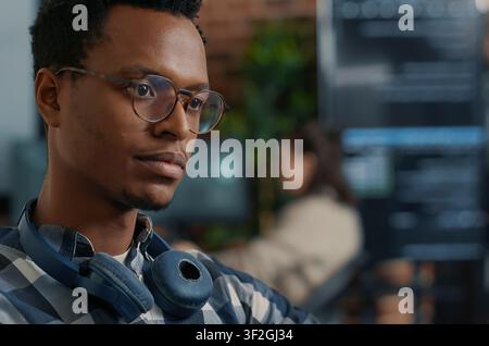 Software Engineer Fixing Glasses While Coding at a software development desk after compiling source code successfully, showing algorithm work and coding success. Stock Photo