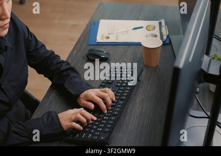 Programmer types source code on a computer keyboard, working at a desk with programming screens, algorithm notes and software development tools. Stock Photo