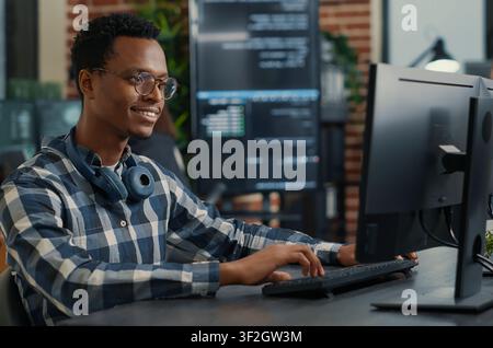 Portrait of software engineer coding software arranging glasses and being happy about parsing results around computer screens, showing developer teamwork, source code discussion and cloud. Stock Photo