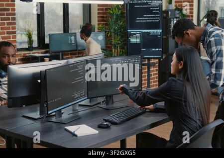 Mixed team of programmers points at screens and compares source code, algorithms and user interface details during a software project review. Stock Photo