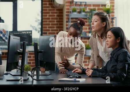 Programmers brainstorm new code library while a developer team discusses algorithms, database work and new software ideas across office computer screens. Stock Photo