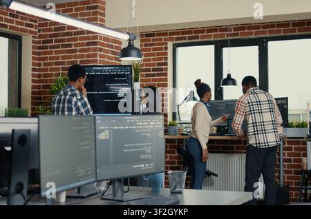 Developers review wall screen code errors as programmers review wall display errors, artificial intelligence code and collaborative debugging inside a software office. Stock Photo