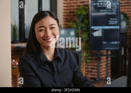 Smiling developer typing machine learning code at desk while developers work with code, terminal windows and digital systems in an IT office focused on software production. Stock Photo