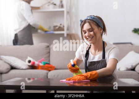 Millennial Couple Making Spring-Cleaning In Flat Together, Woman Wiping Table Stock Photo